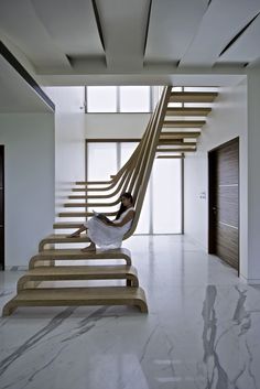 a woman sitting on a wooden stair case in a room with marble floors and walls