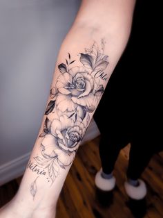 a woman's arm with flowers on it and the word love written in black ink