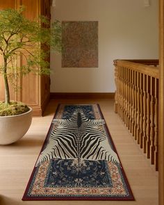 a zebra rug is on the floor next to a potted plant and staircase railing