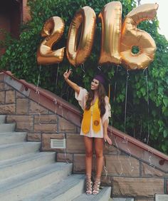 a woman standing on steps with balloons in front of her and the numbers 2013 above her