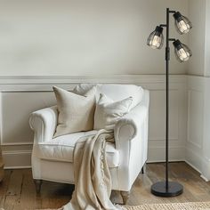 a living room with a white chair, lamp and rug on the wooden flooring