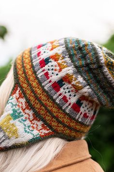 an older woman wearing a multicolored knitted hat looking off into the distance