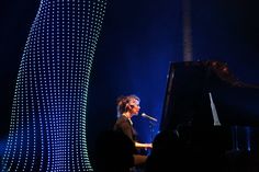 a woman standing next to a piano on stage