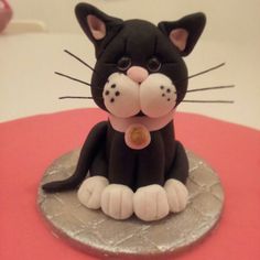 a black and white cat figurine sitting on top of a pink table cloth