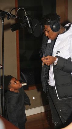 a man standing in front of a microphone next to a little boy wearing headphones