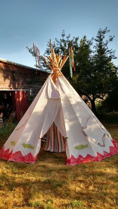 a teepee sitting on top of a grass covered field