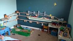 a child's bedroom with toy train tracks on the wall and toys in the floor