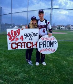 two people standing in the grass holding up signs that say you're a catch prom