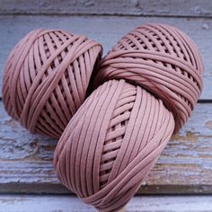 three balls of pink colored yarn sitting on top of a wooden table next to each other