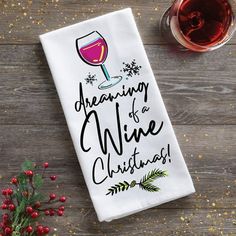 a white towel with the words dreaming wine christmas next to a glass of red wine