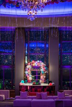 a living room filled with purple couches and chandelier hanging from the ceiling