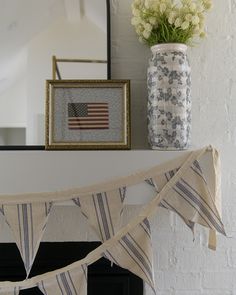 an american flag bunting next to a vase with flowers on the mantel above it