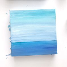 an acrylic painting with blue and white colors on it, next to some paintbrushes