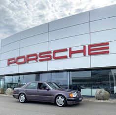 a car parked in front of a porsche dealership