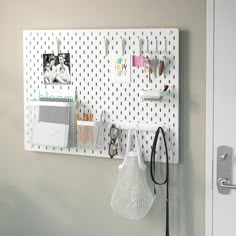 a white pegboard mounted to the side of a wall next to a purse and other items