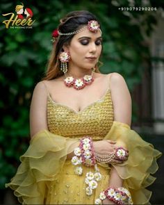 a woman in a yellow dress with flowers on her head and bracelets around her neck