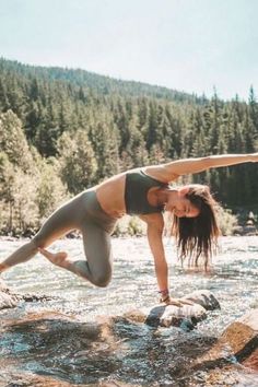 a woman is doing yoga on rocks in the water