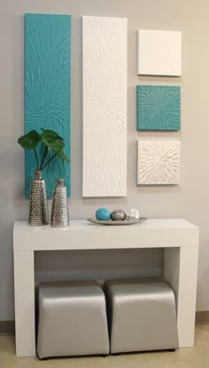 a white table with some vases and paintings on the wall