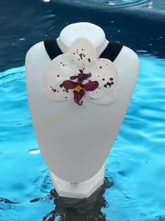 a white vase sitting in the water with a flower on it's back end