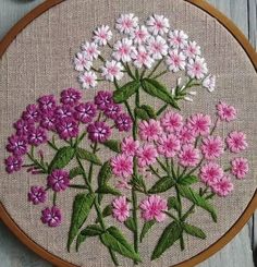 a close up of a embroidery on a wooden hoop with pink and white flowers in it