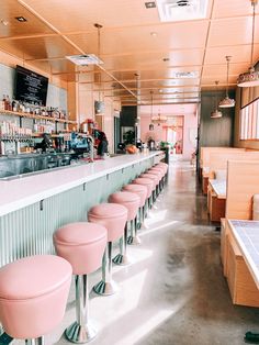 pink stools are lined up in front of the bar at a diner's