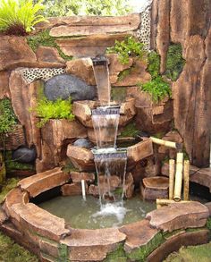 a water fountain surrounded by rocks and plants