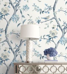 a white lamp sitting on top of a table next to a blue and white wallpaper