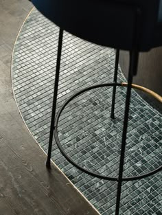 a black chair sitting on top of a wooden floor next to a glass tile wall