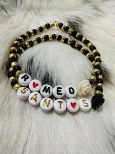 two bracelets with white and black beads that say san francisco on them, sitting on a furry surface