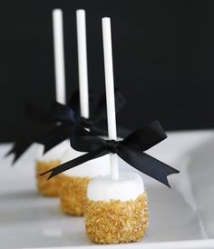 three marshmallow pops with black bows on them