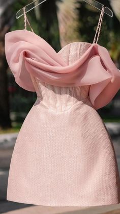 a dress hanging on a clothes rack with a pink scarf draped over it's shoulders