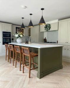 a large kitchen with an island in the middle and four chairs around it on the side