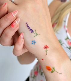 a woman's arm with flowers on it and her hand holding the wrist tattoo