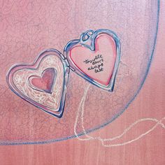 two heart shaped lockes with writing on them sitting on top of a pink surface