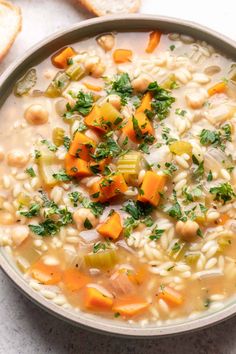 a bowl of soup with carrots, beans and parsley