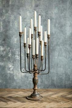 a tall metal candelabra with white candles in it on a wooden table