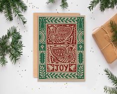 a card with the words joy on it next to christmas presents and evergreen branches,