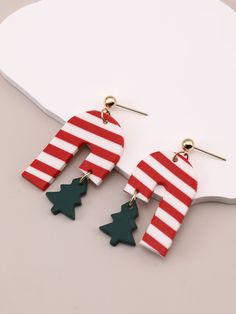 red and white striped wooden earrings with green trees on the bottom, hanging from hooks