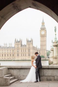 a bride and groom standing in front of the big ben clock tower