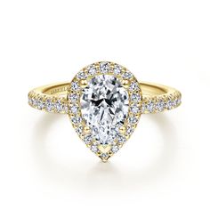 a yellow gold engagement ring with a pear shaped diamond in the center and pave set shoulders