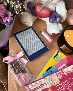 a teddy bear sitting next to a candle, book and other items on a table