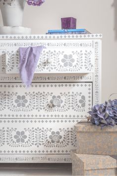 a white dresser with purple flowers on top