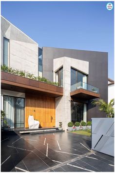 an empty parking lot in front of a modern house with wooden doors and windows on the second floor