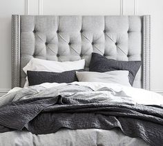 an upholstered bed with pillows and blankets is shown in this black and white photo