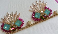 two brooches that are sitting on a piece of cloth with beads and stones