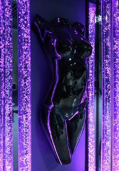 a purple lit up room with a woman's body on the wall and lights behind it