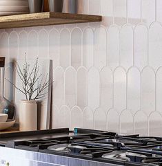 a stove top oven sitting inside of a kitchen next to a shelf filled with pots and pans