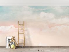 an empty room with a ladder and clouds painted on the wall in pastel colors