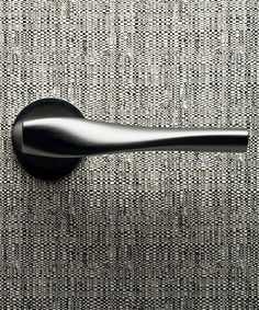 a black door handle on the side of a gray fabric wallpapered room with vertical stripes