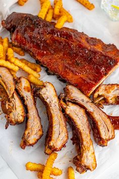 ribs and french fries are sitting on a paper towel next to some ketchup